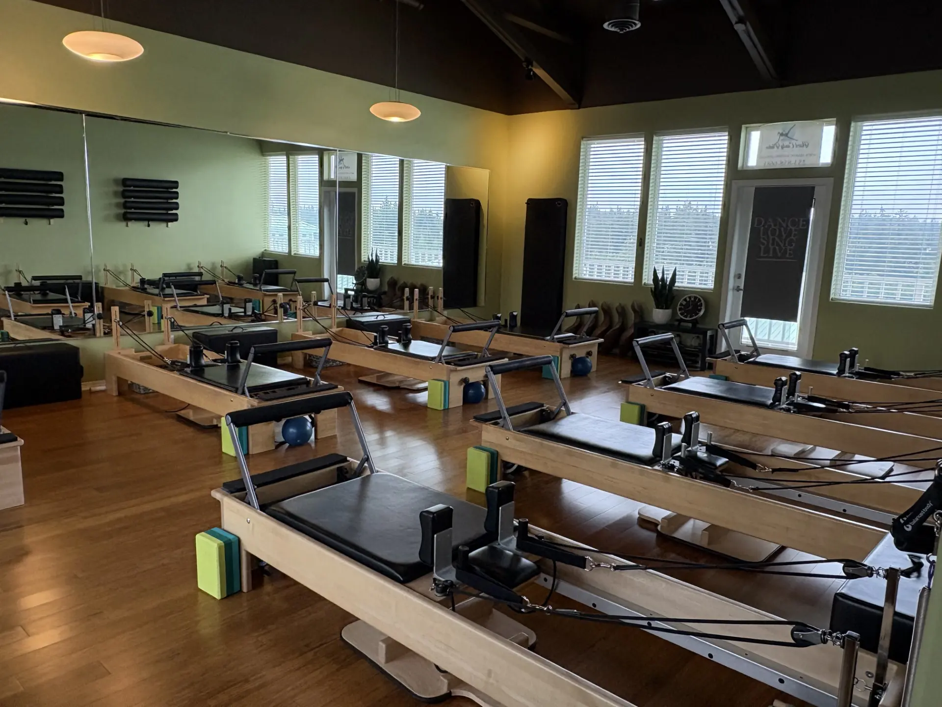 Row of wooden reformers on a hardwood floor in the SLOW burn Pilates studio